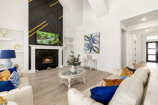 6523 Poplar Meadow Ln, Katy, TX 77493 - living room featuring built in features, light wood-type flooring, a glass covered fireplace, a high ceiling, and recessed lighting