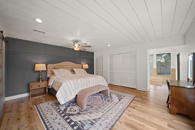 15722 Falmouth Dr, Houston, TX 77059 - bedroom with light wood-style floors, two closets, recessed lighting, a barn door, and ceiling fan