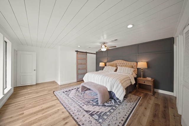 15722 Falmouth Dr, Houston, TX 77059 - bedroom with a barn door, light wood-type flooring, wooden ceiling, a ceiling fan, and recessed lighting