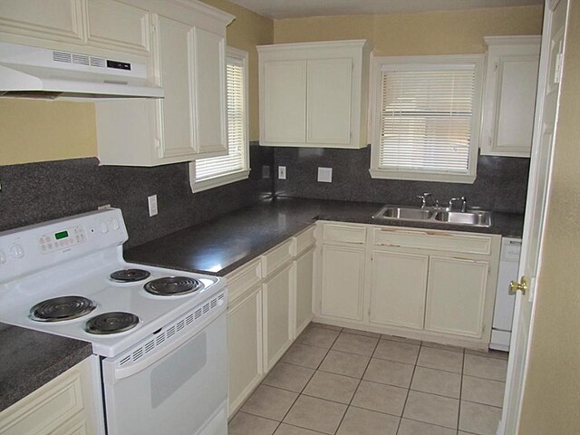 4911 Delano St, Houston, TX 77004 - kitchen with white appliances, under cabinet range hood, dark countertops, and light tile patterned floors