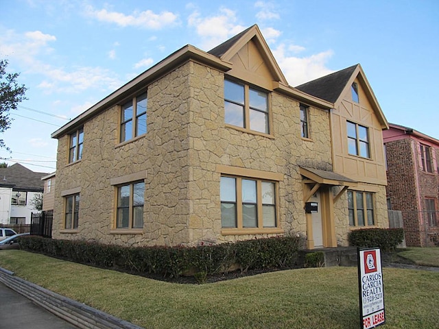 4911 Delano St, Houston, TX 77004 - view of front facade with stone siding, a front yard, and board and batten siding