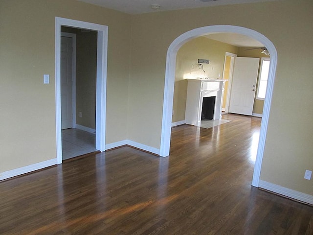 4911 Delano St, Houston, TX 77004 - unfurnished room featuring arched walkways, dark wood-style floors, a fireplace with flush hearth, and a smoke detector
