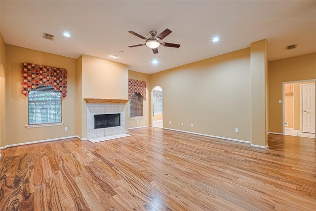 3803 Doveswood Cir, Needville, TX 77461 - unfurnished living room featuring light wood-type flooring, a ceiling fan, a tile fireplace, recessed lighting, and arched walkways