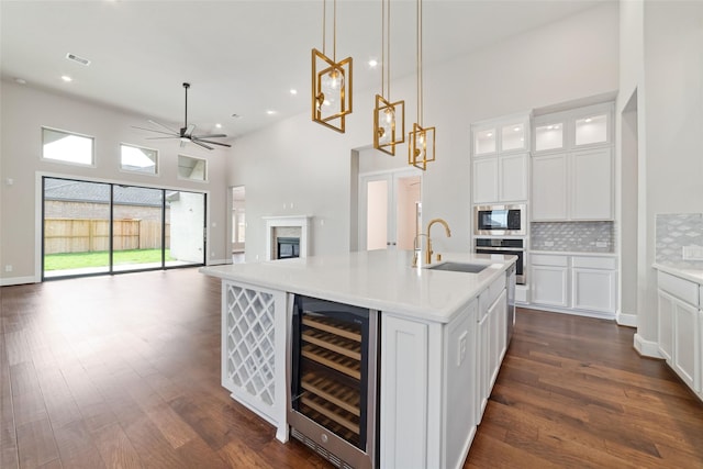 12722 Noble Fields Way, Cypress, TX 77433 - kitchen featuring beverage cooler, a towering ceiling, a ceiling fan, backsplash, and white cabinets