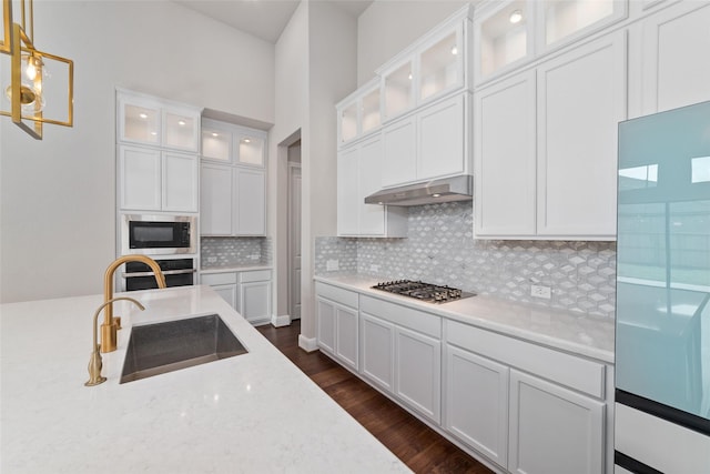 12722 Noble Fields Way, Cypress, TX 77433 - kitchen featuring appliances with stainless steel finishes, under cabinet range hood, tasteful backsplash, white cabinets, and decorative light fixtures