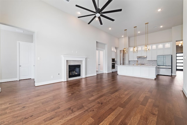 12722 Noble Fields Way, Cypress, TX 77433 - unfurnished living room featuring a ceiling fan, dark wood finished floors, recessed lighting, a glass covered fireplace, and a high ceiling