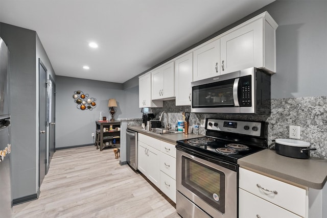 3101 Yost Blvd, Pearland, TX 77581 - kitchen with appliances with stainless steel finishes, decorative backsplash, light wood-type flooring, white cabinets, and recessed lighting