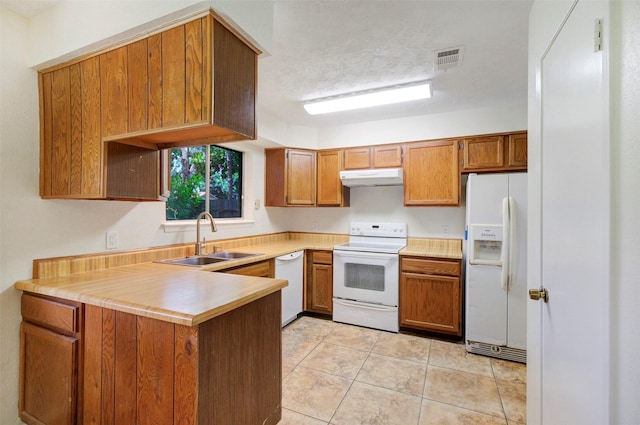 10314 Paintbrush Ln, Sugar Land, TX 77498 - kitchen with white appliances, under cabinet range hood, a peninsula, brown cabinets, and light countertops