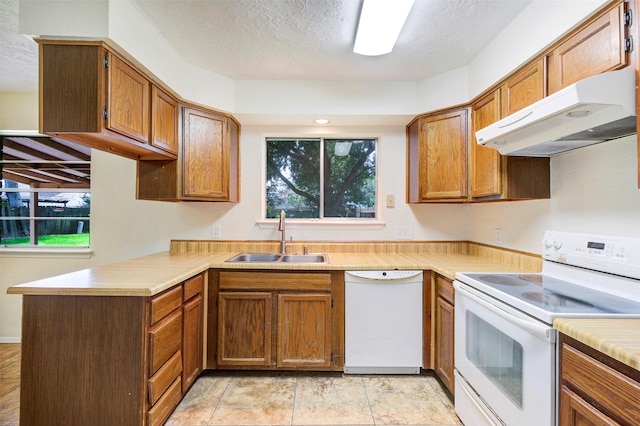 10314 Paintbrush Ln, Sugar Land, TX 77498 - kitchen featuring white appliances, under cabinet range hood, light countertops, brown cabinets, and a textured ceiling