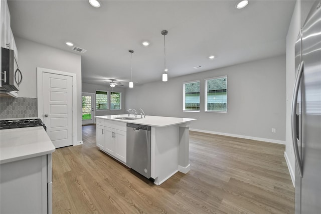 6609 Lahna Oak Dr, Conroe, TX 77304 - kitchen featuring appliances with stainless steel finishes, recessed lighting, white cabinets, light wood-style flooring, and a center island with sink