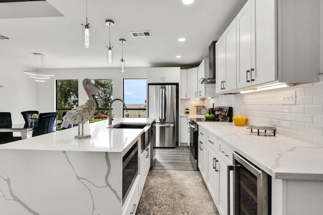118 Hickory Pnes, Livingston, TX 77351 - kitchen featuring appliances with stainless steel finishes, wine cooler, wall chimney range hood, pendant lighting, and backsplash