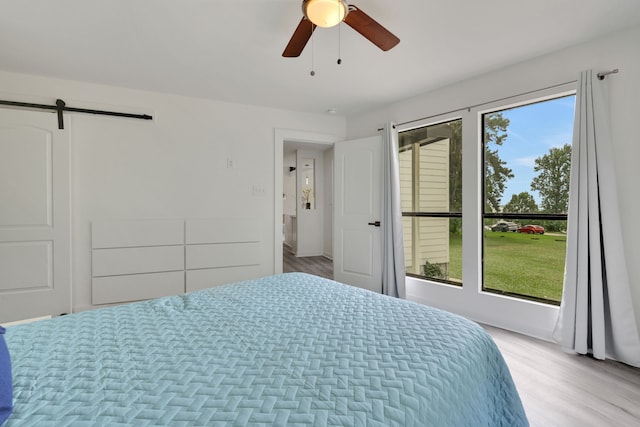 118 Hickory Pnes, Livingston, TX 77351 - bedroom with multiple windows, a barn door, light wood-type flooring, and ceiling fan