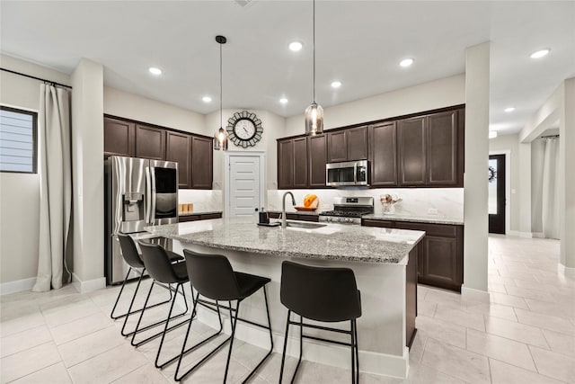 15247 Parkland Canyon Dr, Cypress, TX 77433 - kitchen featuring appliances with stainless steel finishes, dark brown cabinets, light tile patterned flooring, a kitchen breakfast bar, and recessed lighting