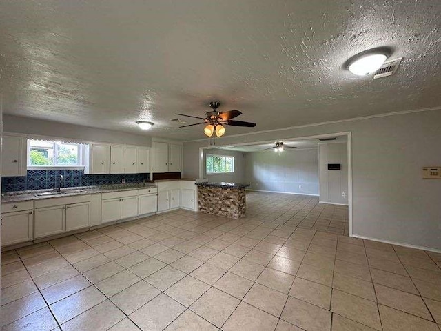 7717 Bigwood St, Houston, TX 77016 - kitchen with ceiling fan, a textured ceiling, plenty of natural light, light tile patterned flooring, and a peninsula