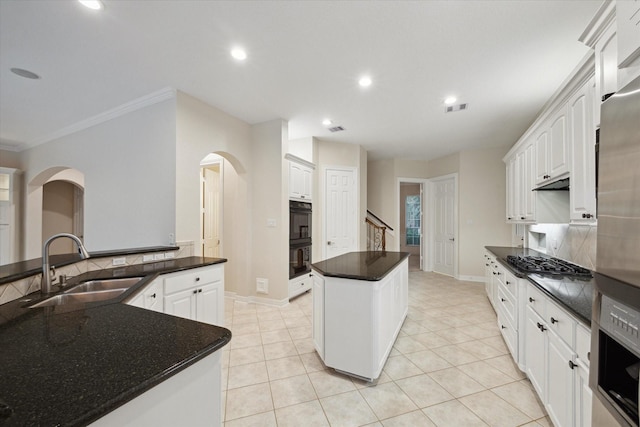 15411 Driftwood Oak Ct, Houston, TX 77059 - kitchen featuring stainless steel gas cooktop, a kitchen island, arched walkways, crown molding, and white cabinetry