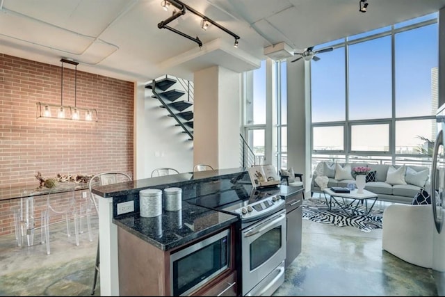 2000 Bagby St Unit 9420, Houston, TX 77002 - kitchen with stainless steel appliances, finished concrete flooring, brick wall, dark stone countertops, and track lighting