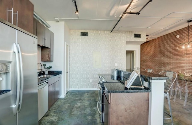 2000 Bagby St Unit 9420, Houston, TX 77002 - kitchen featuring appliances with stainless steel finishes, unfinished concrete flooring, a breakfast bar area, brick wall, and dark stone counters