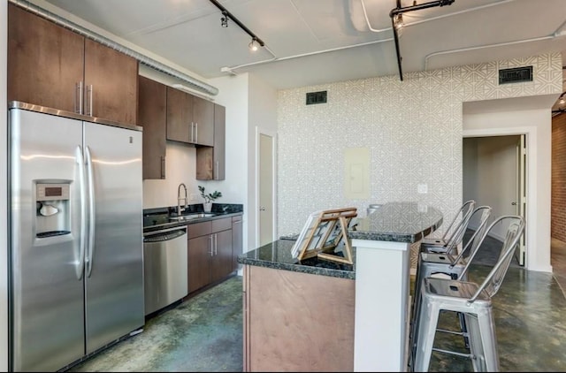 2000 Bagby St Unit 9420, Houston, TX 77002 - kitchen with stainless steel appliances, finished concrete floors, rail lighting, a breakfast bar area, and dark brown cabinets