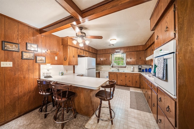 91 E Post Oak Ln, Shepherd, TX 77371 - kitchen featuring white appliances, brown cabinets, a peninsula, light countertops, and wooden walls
