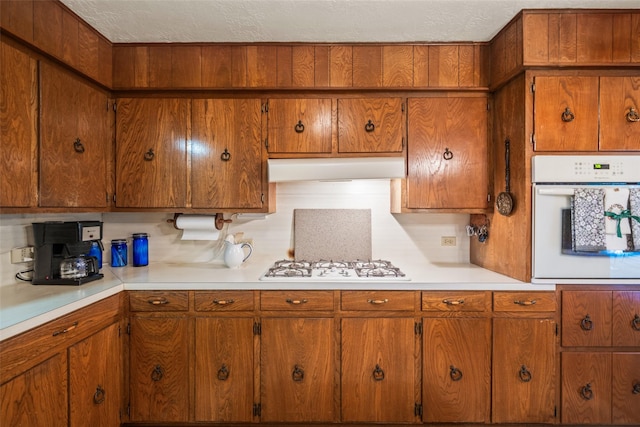 91 E Post Oak Ln, Shepherd, TX 77371 - kitchen with white appliances, light countertops, brown cabinetry, and a textured ceiling