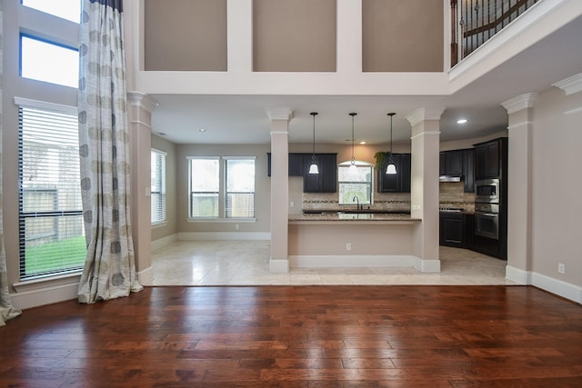 6034 Gracys Landing Ln, Katy, TX 77494 - unfurnished living room with ornate columns, light wood-style flooring, a high ceiling, and recessed lighting
