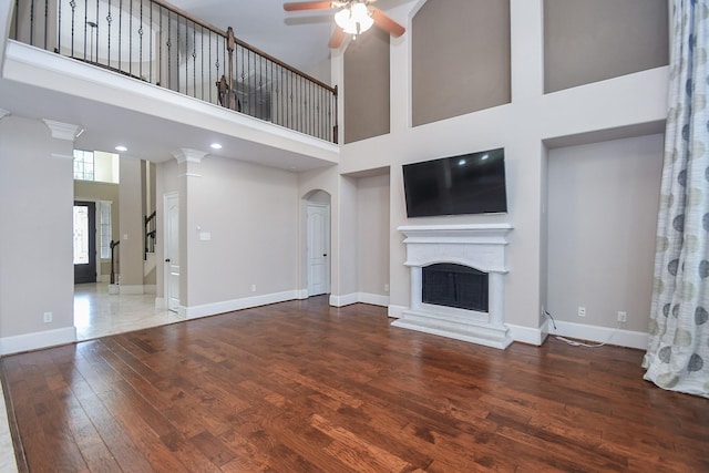 6034 Gracys Landing Ln, Katy, TX 77494 - unfurnished living room with ceiling fan, wood finished floors, a high ceiling, arched walkways, and a fireplace with raised hearth