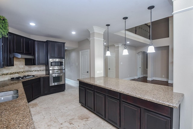 6034 Gracys Landing Ln, Katy, TX 77494 - kitchen with appliances with stainless steel finishes, light stone counters, backsplash, ornate columns, and under cabinet range hood