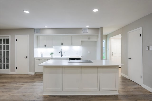 10260 Field Stone Dr, Houston, TX 77041 - kitchen featuring white cabinets, black electric cooktop, light countertops, recessed lighting, and light wood-style flooring