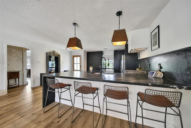 5503 Cheshire Ln, Houston, TX 77092 - kitchen with a peninsula, dark countertops, backsplash, light wood finished floors, and a textured ceiling