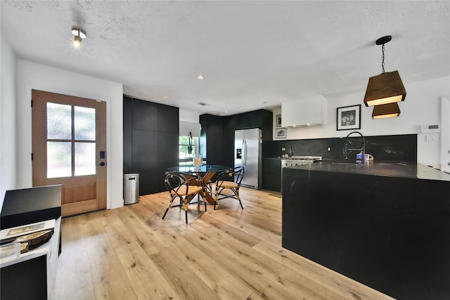 5503 Cheshire Ln, Houston, TX 77092 - kitchen with dark cabinetry, stainless steel refrigerator with ice dispenser, plenty of natural light, light wood-type flooring, and a textured ceiling