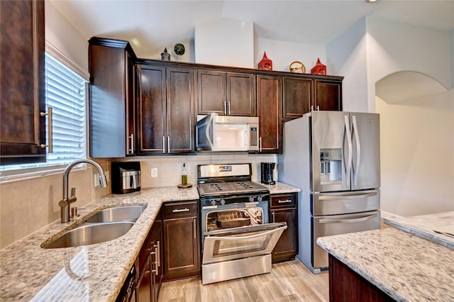 5311 Persimmon Pass, Richmond, TX 77407 - kitchen with appliances with stainless steel finishes, light stone counters, dark brown cabinetry, and light wood-style flooring