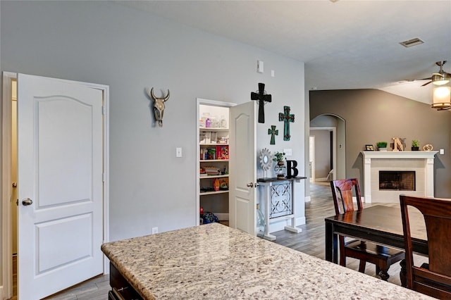 5311 Persimmon Pass, Richmond, TX 77407 - kitchen featuring dark wood-style floors, ceiling fan, arched walkways, a fireplace, and lofted ceiling