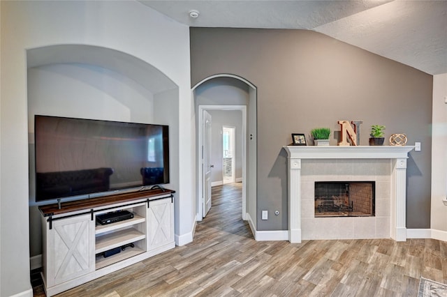 5311 Persimmon Pass, Richmond, TX 77407 - living area featuring vaulted ceiling, a tiled fireplace, and wood finished floors