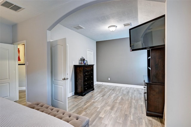 5311 Persimmon Pass, Richmond, TX 77407 - bedroom featuring arched walkways, light wood-style flooring, and a textured ceiling