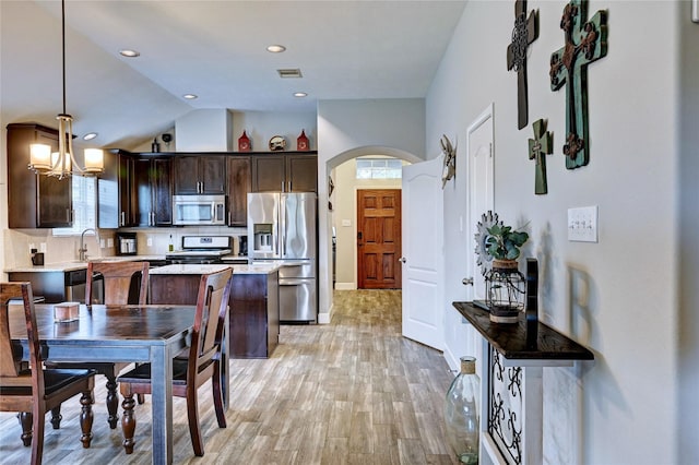 5311 Persimmon Pass, Richmond, TX 77407 - kitchen featuring stainless steel appliances, a kitchen island, dark brown cabinets, arched walkways, and lofted ceiling