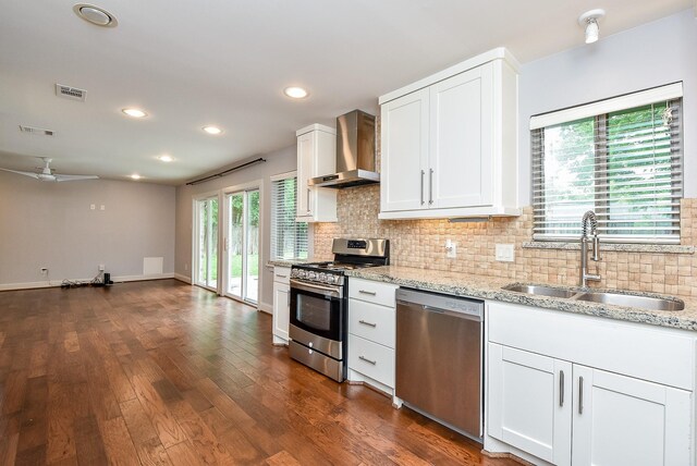 5815 Dryad Dr, Houston, TX 77035 - kitchen with appliances with stainless steel finishes, wall chimney range hood, tasteful backsplash, light stone counters, and recessed lighting