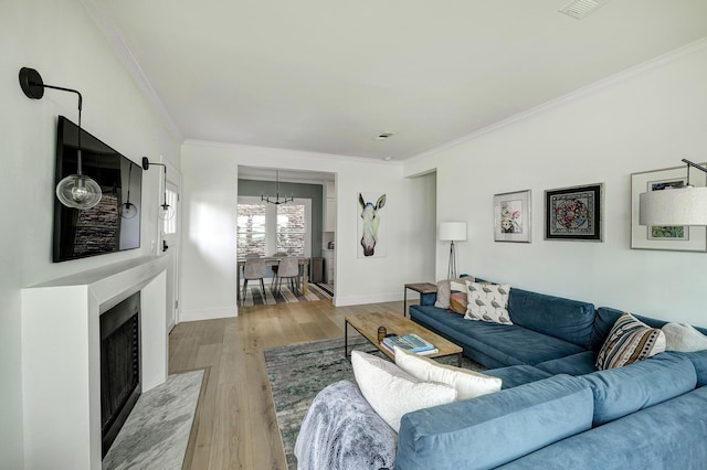 1917 Brun St, Houston, TX 77019 - living room with a chandelier, ornamental molding, light wood-style flooring, and a fireplace with flush hearth