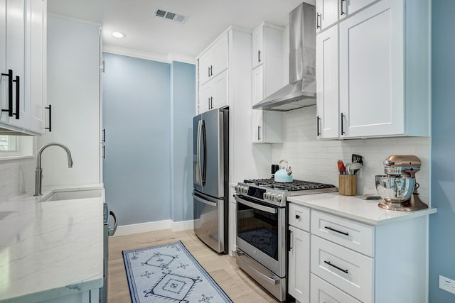 1917 Brun St, Houston, TX 77019 - kitchen with wall chimney range hood, stainless steel appliances, tasteful backsplash, light stone countertops, and white cabinets
