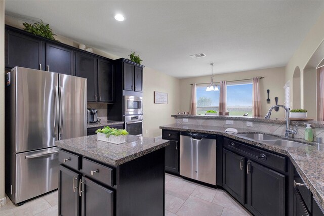 7518 Tejas Lakes Trl, Needville, TX 77461 - kitchen with stainless steel appliances, a kitchen island, dark stone counters, tasteful backsplash, and light tile patterned floors