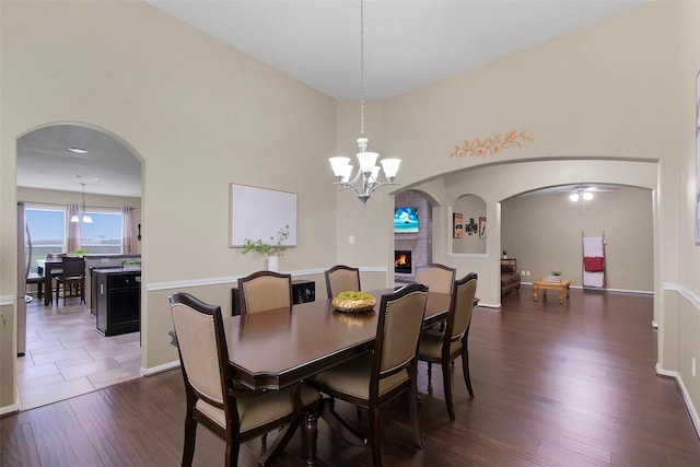 7518 Tejas Lakes Trl, Needville, TX 77461 - dining area with a chandelier, dark wood-style flooring, arched walkways, and a fireplace