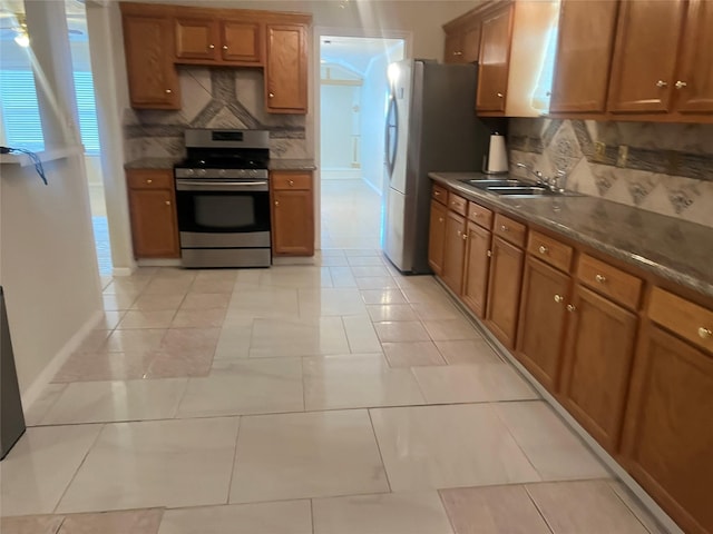 7001 Kassarine Pass, Houston, TX 77033 - kitchen featuring stainless steel appliances, brown cabinets, dark countertops, and tasteful backsplash