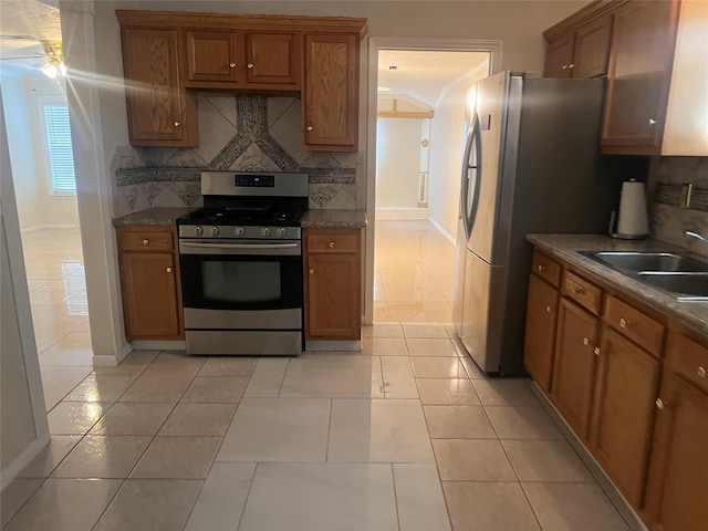 7001 Kassarine Pass, Houston, TX 77033 - kitchen featuring stainless steel gas range oven, brown cabinetry, backsplash, and light tile patterned floors