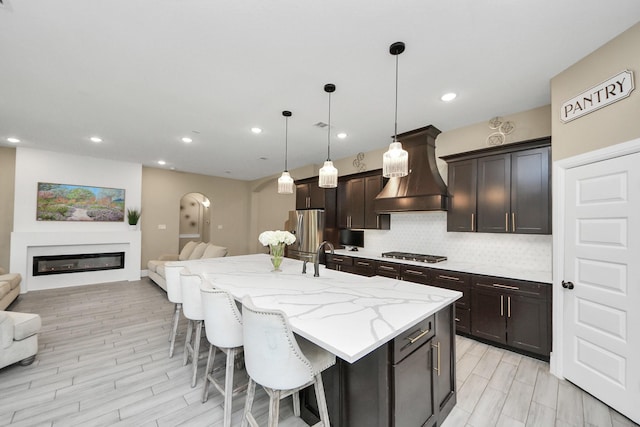 203 Pinedale Ave, Arcola, TX 77583 - kitchen featuring premium range hood, appliances with stainless steel finishes, arched walkways, open floor plan, and recessed lighting