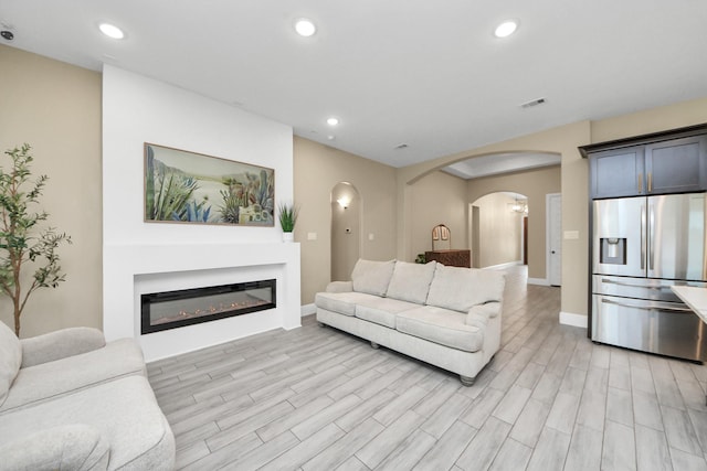 203 Pinedale Ave, Arcola, TX 77583 - living area with arched walkways, a glass covered fireplace, light wood-style floors, and recessed lighting