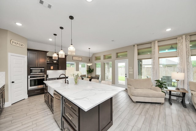 203 Pinedale Ave, Arcola, TX 77583 - kitchen with appliances with stainless steel finishes, a center island with sink, open shelves, open floor plan, and dark brown cabinets