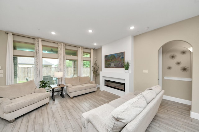 203 Pinedale Ave, Arcola, TX 77583 - living area featuring light wood-style floors, plenty of natural light, a glass covered fireplace, arched walkways, and recessed lighting
