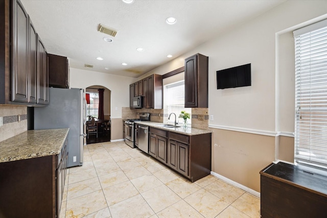 6111 Branch Lake Dr, Houston, TX 77066 - kitchen with stainless steel appliances, arched walkways, backsplash, dark brown cabinets, and recessed lighting