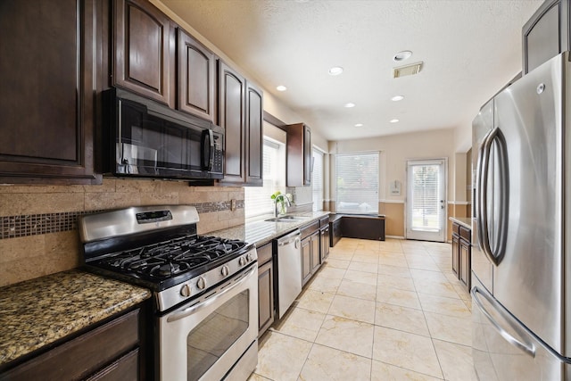 6111 Branch Lake Dr, Houston, TX 77066 - kitchen featuring stainless steel appliances, dark stone counters, dark brown cabinets, decorative backsplash, and recessed lighting