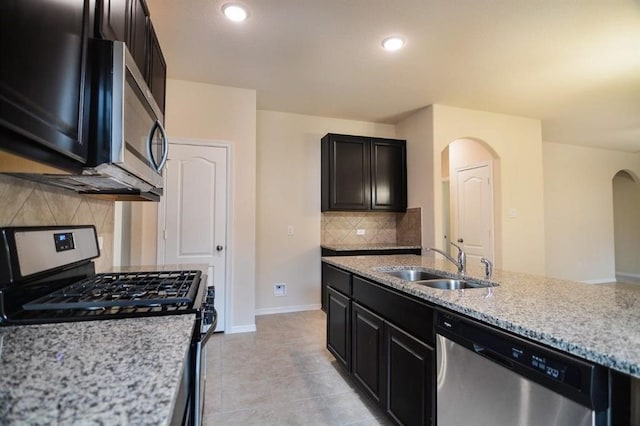 2135 Republic Way, Missouri City, TX 77489 - kitchen with stainless steel appliances, arched walkways, backsplash, light stone countertops, and dark cabinets