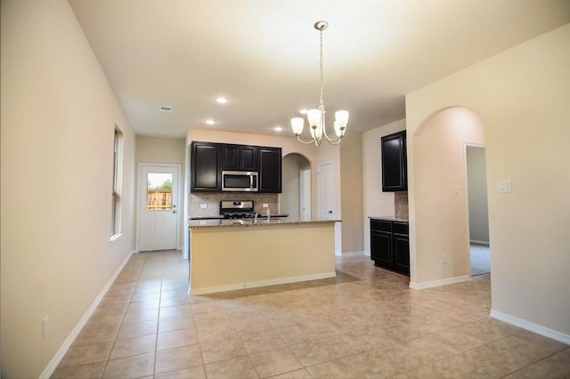 2135 Republic Way, Missouri City, TX 77489 - kitchen featuring stainless steel appliances, arched walkways, dark cabinets, tasteful backsplash, and a chandelier